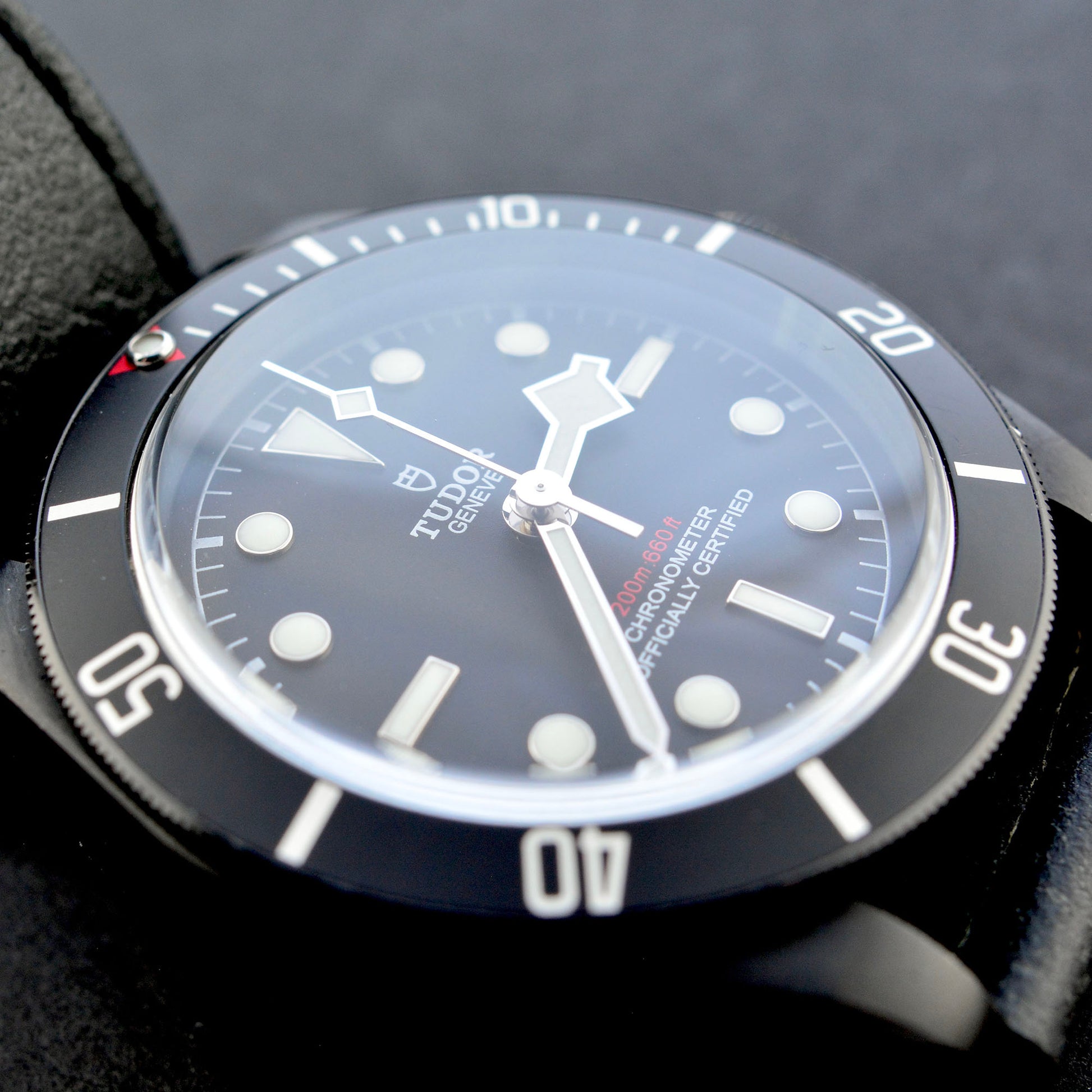 Close-up of a Tudor watch with a black strap and blue dial.