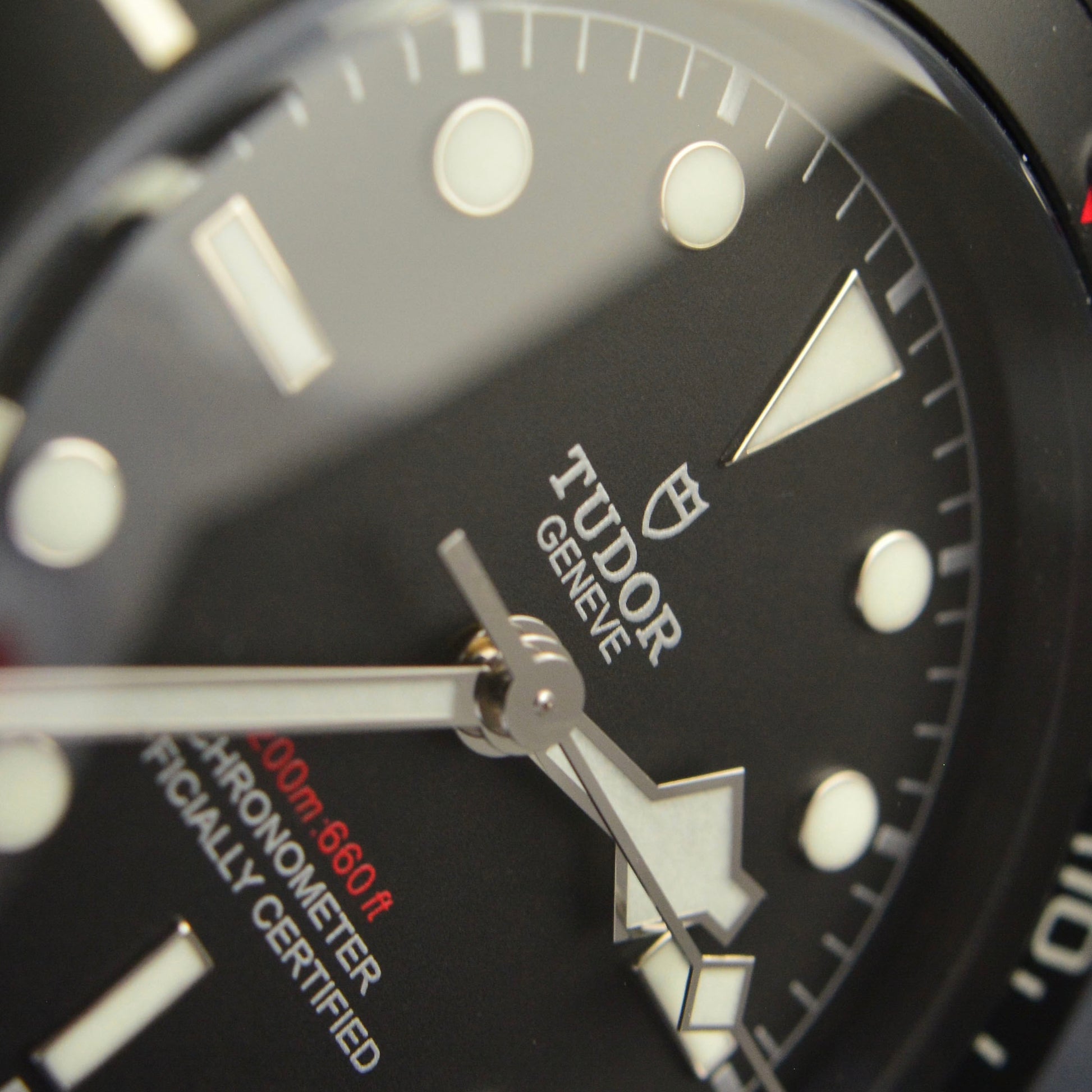 Close-up of a Tudor watch face with black dial and visible brand logo.
