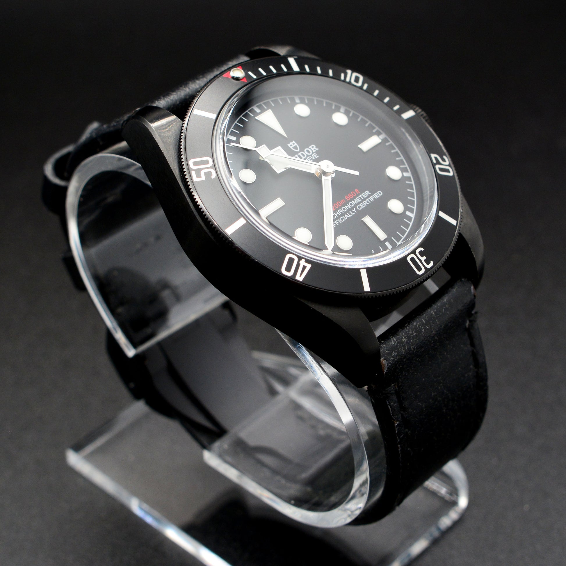 Black wristwatch on a stand with a dark background