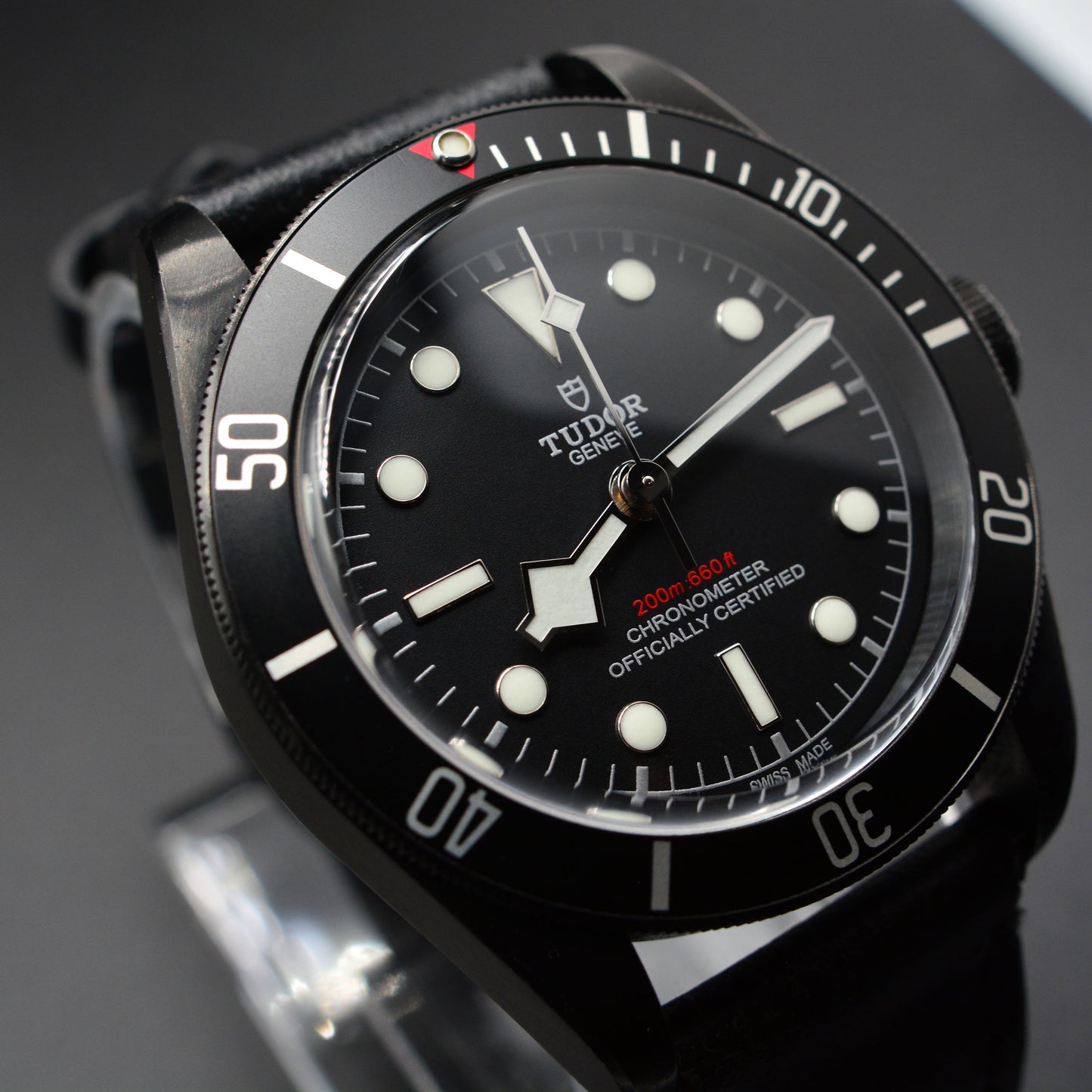 Black Tudor watch with a detailed face on a dark background