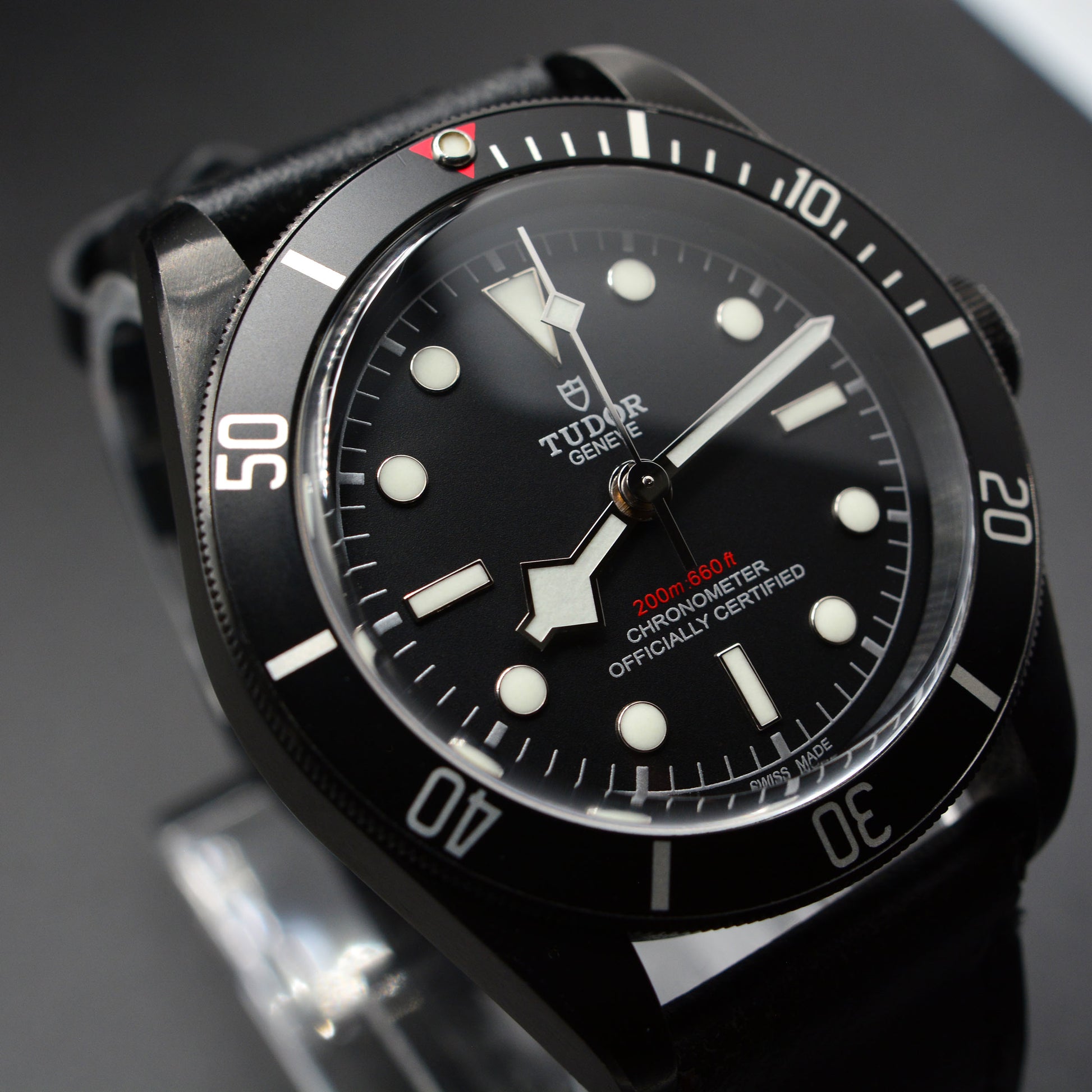 Black Tudor watch with a detailed face on a dark background