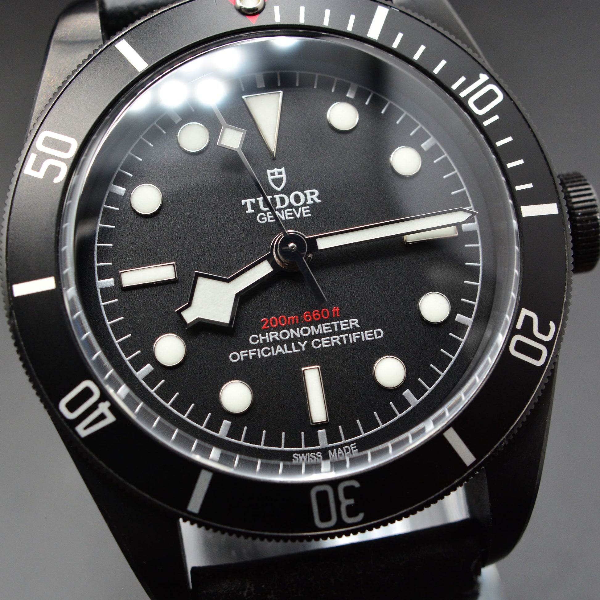 Black Tudor watch with detailed face on a dark background